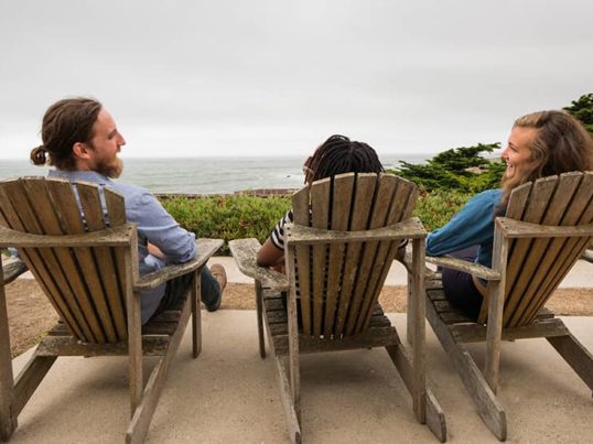 travelers relaxing in adirondack chairs at HI Pigeon Point Lighthouse