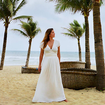 writer lola mendez in a white dress on the beach