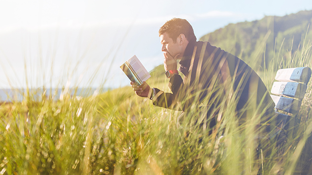 a man reading a book outside