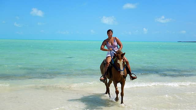 the author Jessica van Dop DeJesus on horseback in the water in Turks and Caicos