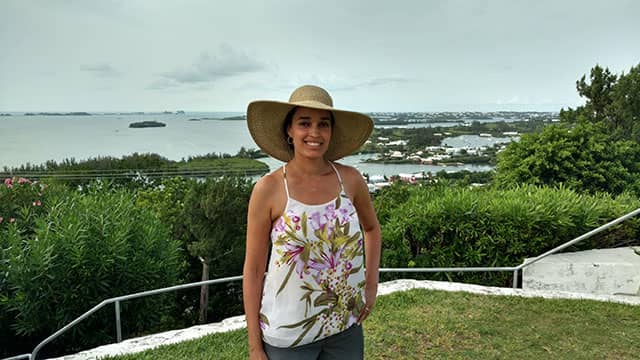 journalist Tinabeth Pina wearing a wide-brimmed hat overlooking the water in Bermuda