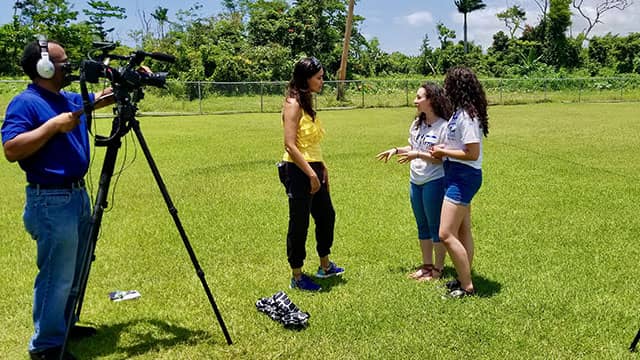 journalist Tinabeth Pina speaks with students while being filmed in Puerto Rico