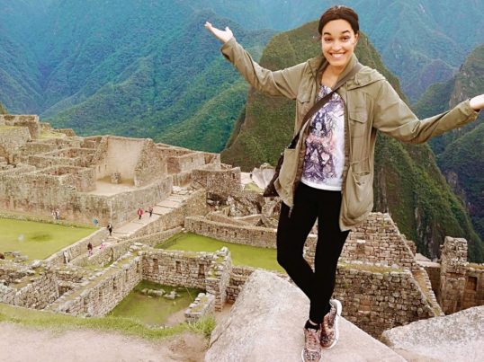 the author Tinabeth Pina in Peru overlooking ruins in the mountains