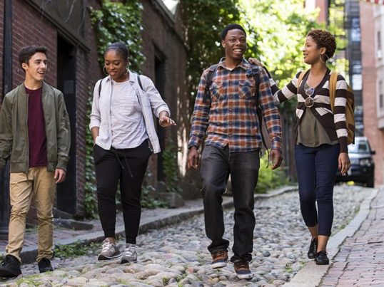 a group of young people walks down a narrow street in Boston's Beacon Hill neighborhood