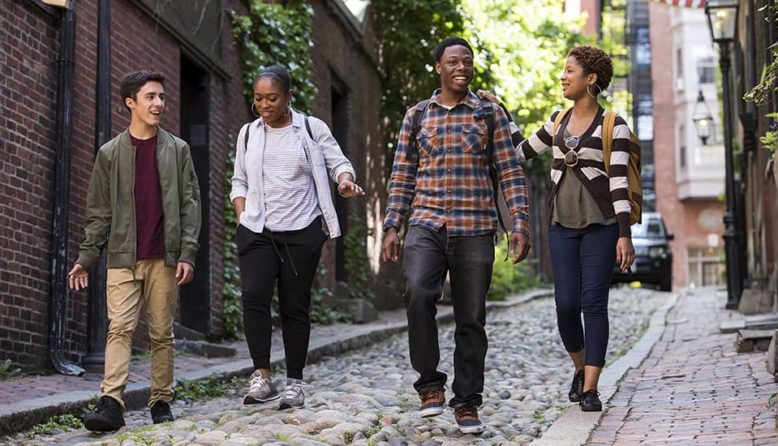 a group of young people walks down a narrow street in Boston's Beacon Hill neighborhood