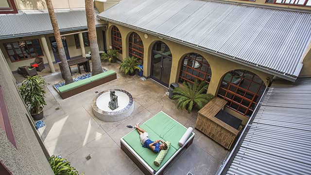a man lies on an outdoor couch in the sun in HI Los Angeles Santa Monica's courtyard