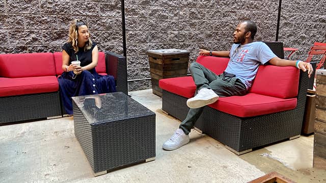 two people sit talking at a distance in the outdoor courtyard at a HI USA hostel