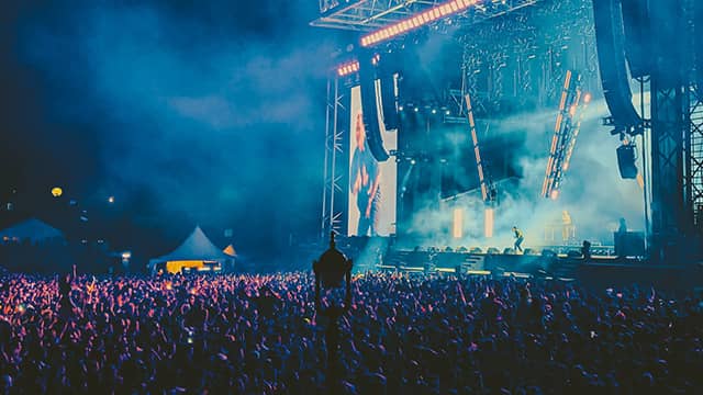 a crowd watches an outdoor concert at night