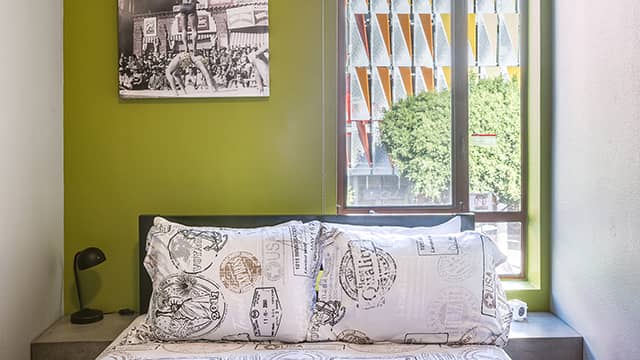 a double-sized bed with a view of a colorful building out the window at HI Los Angeles Santa Monica