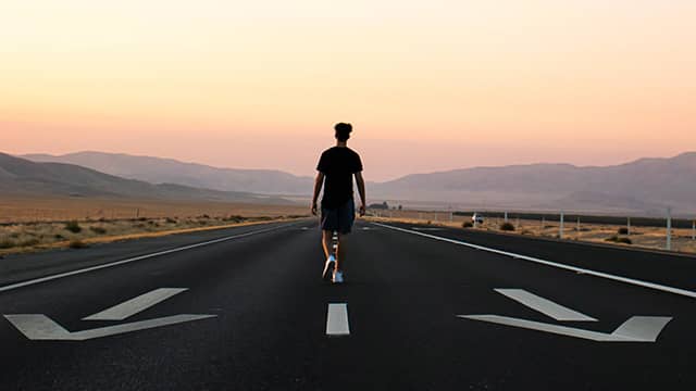 a man walks away from the camera at sunset