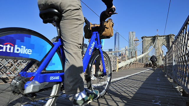 a cyclist on a citi bike crosses the brooklyn bridge in New York