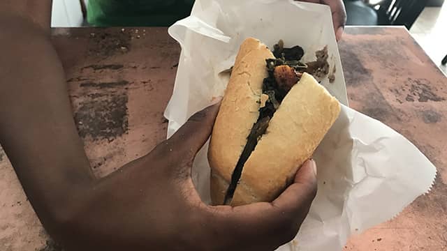 a woman holds a po' boy sandwich in new orleans