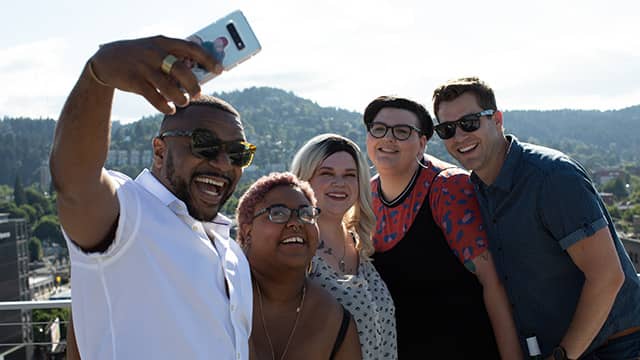 a group of five people take a selfie in front of a mountain