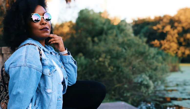 a woman wearing a jean jacket and sunglasses looking out over a body of water at New Orleans' City Park