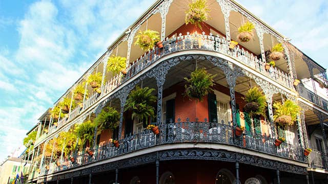 a building in New Orleans' French Quarter with plants overhanging the balconies