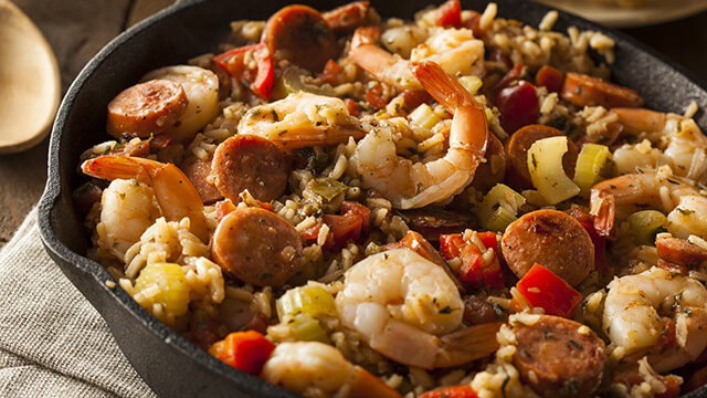 a close-up of a cast iron pan containing a colorful New Orleans gumbo with shrimp and sausage