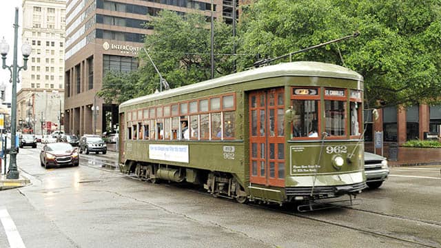 a green streetcar drives down the road