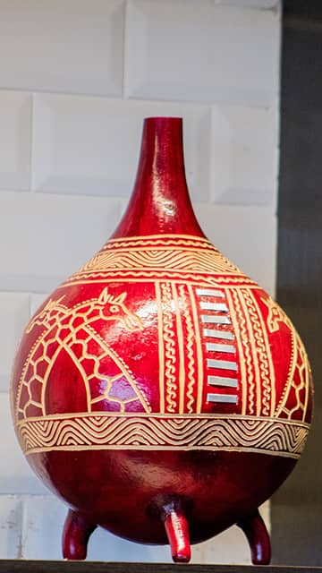a red and white kenyan jug with images of giraffes