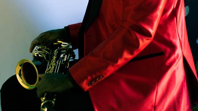 a man in a red jacket holds a saxophone