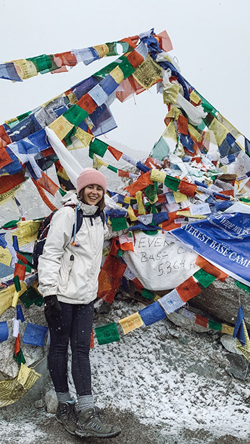 a young woman in front of brightly colored flags at Mount Everest Base Camp