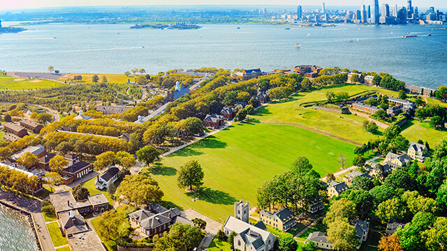 an aerial view of governor's island, an expansive green space, with a view of the Manhattan skyline across the water