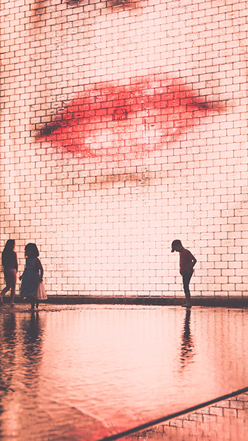 people stand in front of an illuminated screen showing a woman's face