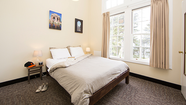a private room with a large bed and fresh linens and a window overlooking the park