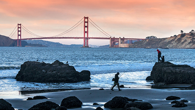 an orange sky at sunset behind the golden gate bridge