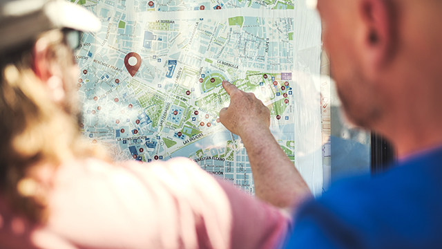 two people seen from behind look at a vertical city map