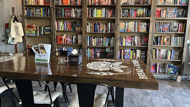a long wooden table in front of shelves stacked with colorful books at bread and roses cafe in hyannis massachusetts