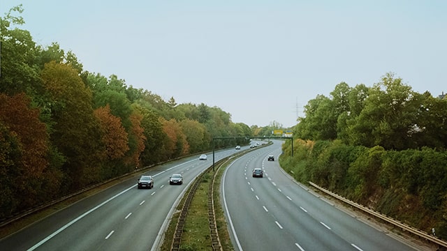 a highway surrounded by trees with several cars heading in opposite directions