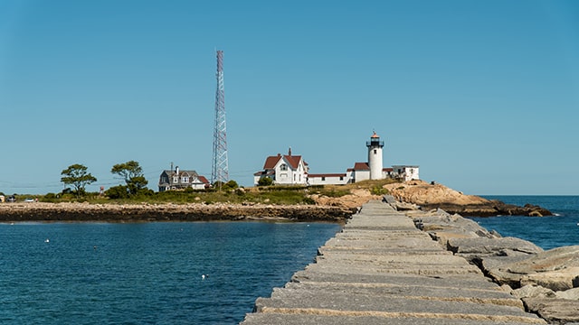 a long boardwalk leading to a white lighthouse and surrounding buildings