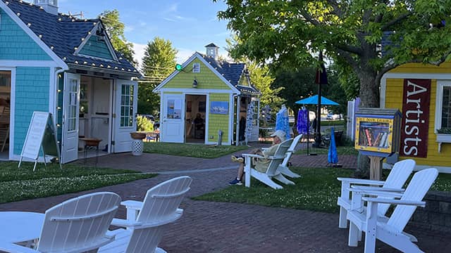 yellow and blue artist shanties with white adirondack chairs in front in hyannis massachusetts