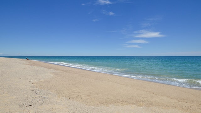 a white sandy beach with light blue ocean water