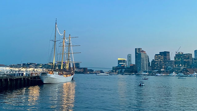 a view of the boston skyline at night from east boston with a tall ship in the foreground