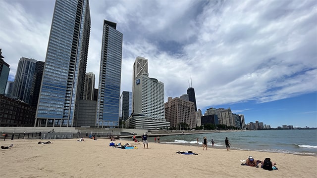 people relax on the sandy beach with the chicago skyline in the background