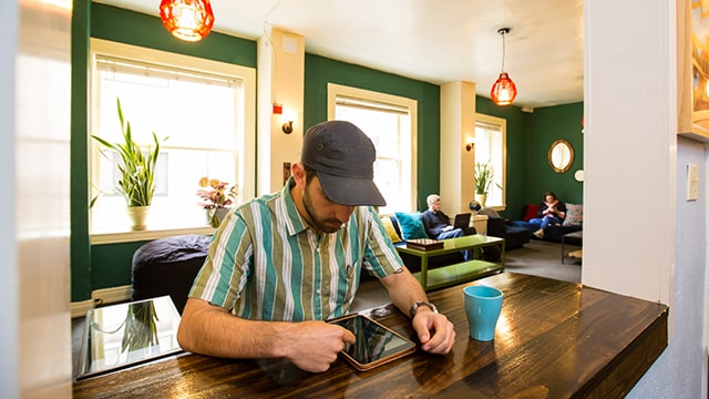 a traveler works quietly on a tablet in a hostel lounge