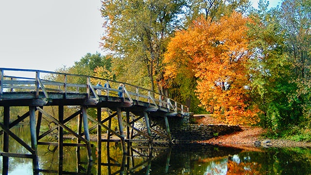 orange and yellow fall foliage at the old north bridge in Concord MA