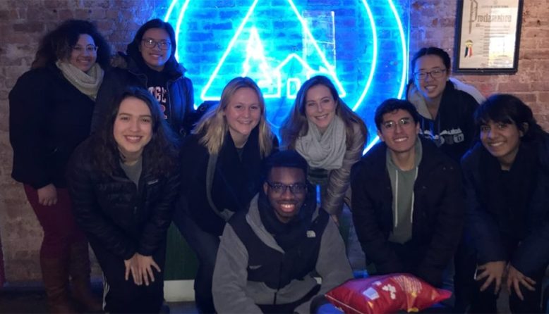 a group of volunteers pose in front of a neon sign in New York City