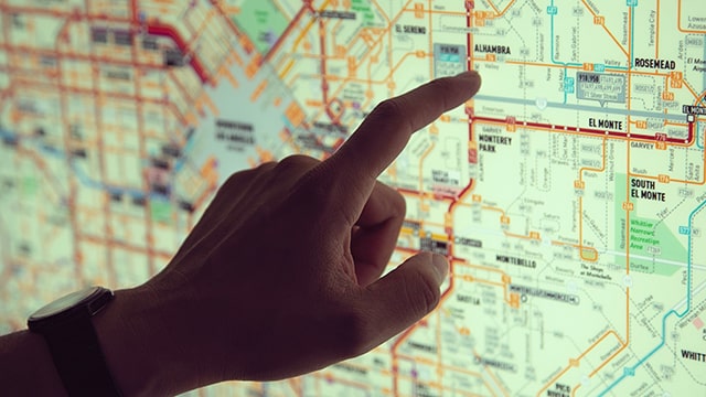 a hand points to a stop on the los angeles metro map