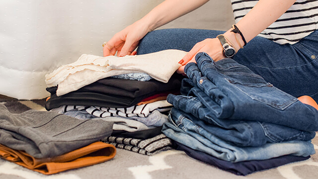 two hands stacking folded clothing