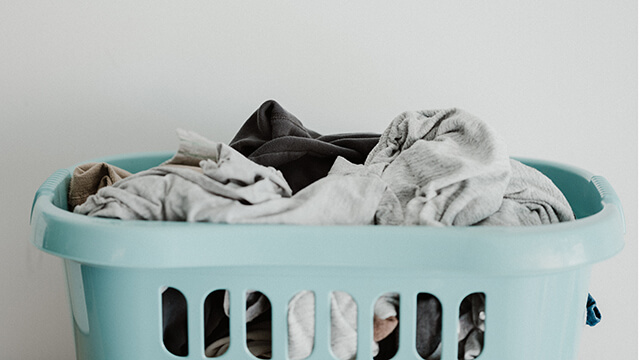 a small blue laundry basket filled with clothes