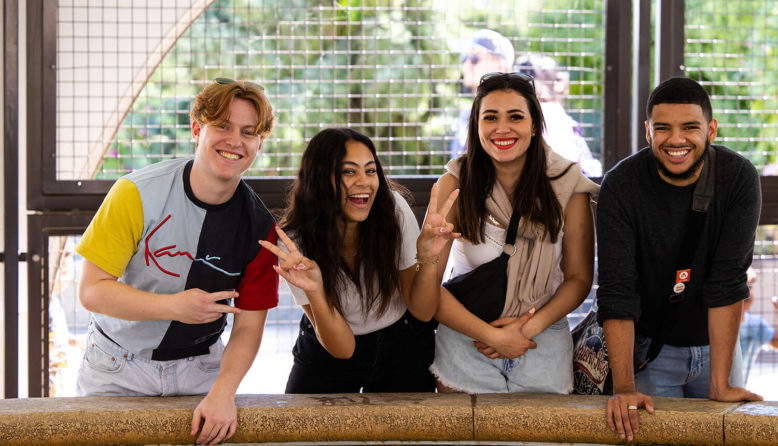 two young men and two young women participating in an international exchange stand smiling next to each other while interacting at an aquarium