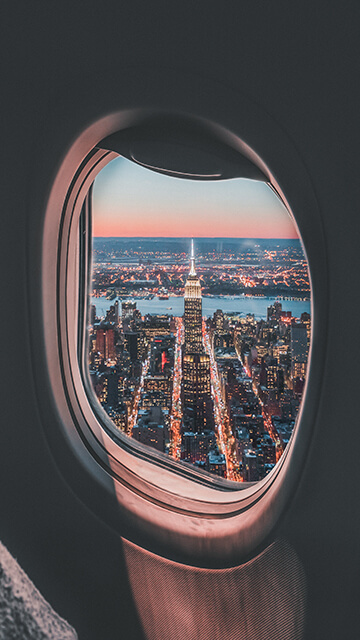 a view out an airplane window of a city lit up at night