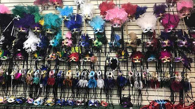 Rows of colorful Mardi Gras masks hang on a wall