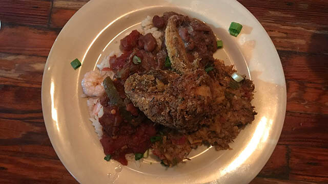 a plate of fried food over sauce and rice with shrimp in new orleans