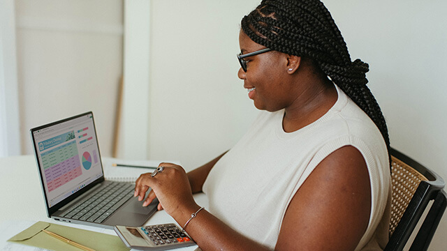 a woman working at a laptop with a calculator