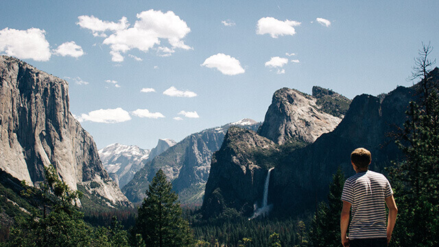 a man in a striped shirt looks out over Yosemite