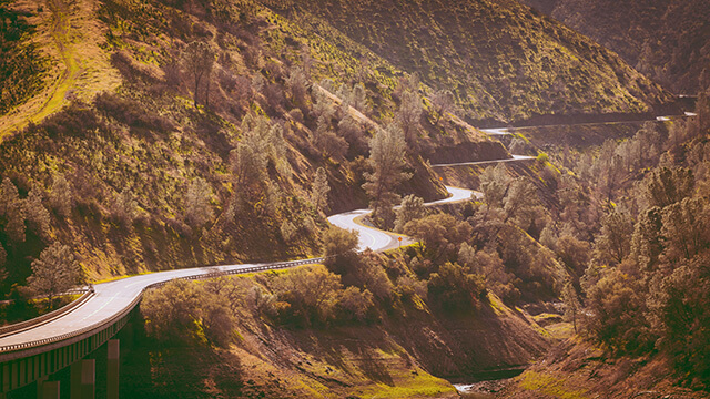 a winding road through mountains covered in green trees