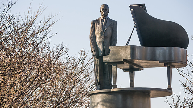 a statue of the legendary musician Duke Ellington standing in front of a piano in Harlem, New York City